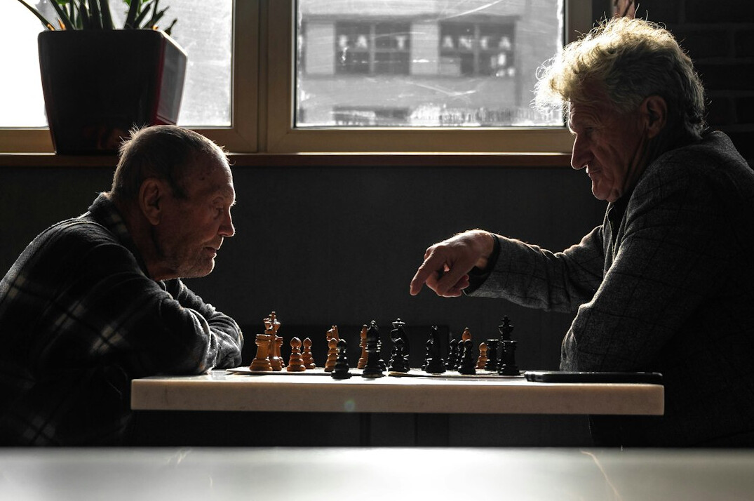 Two senior men playing chess and concentrating on the board