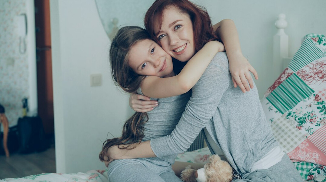 Adult daughter visiting and hugging her senior mother at home