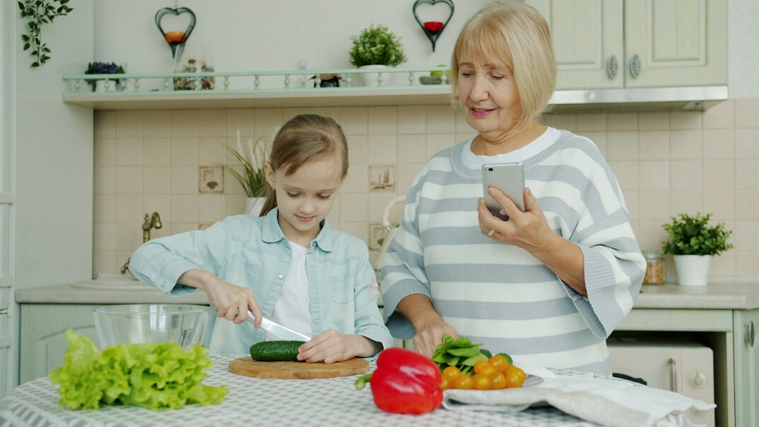 Two senior women cooking together in a kitchen and smiling